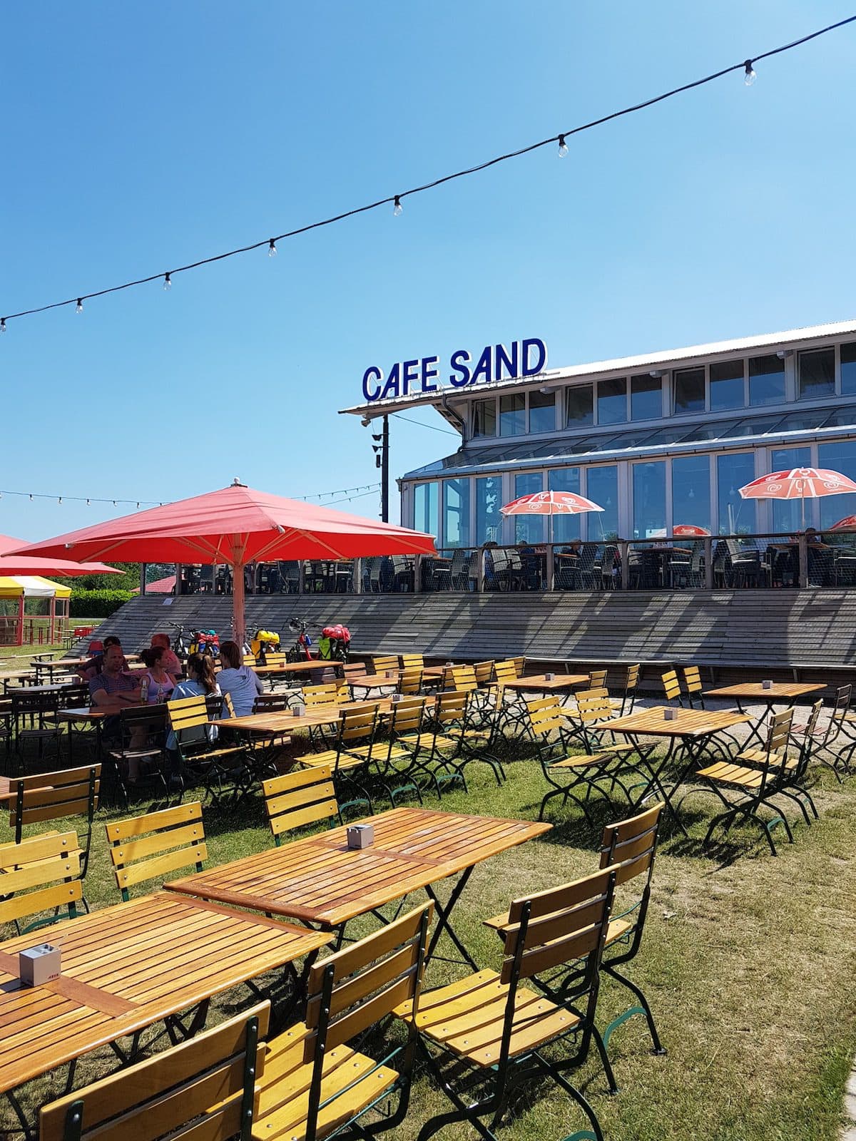 Die Terrasse mit vom Cafe Sand in Bremen - mit Biergartenstühlen und Sonnenschirmen