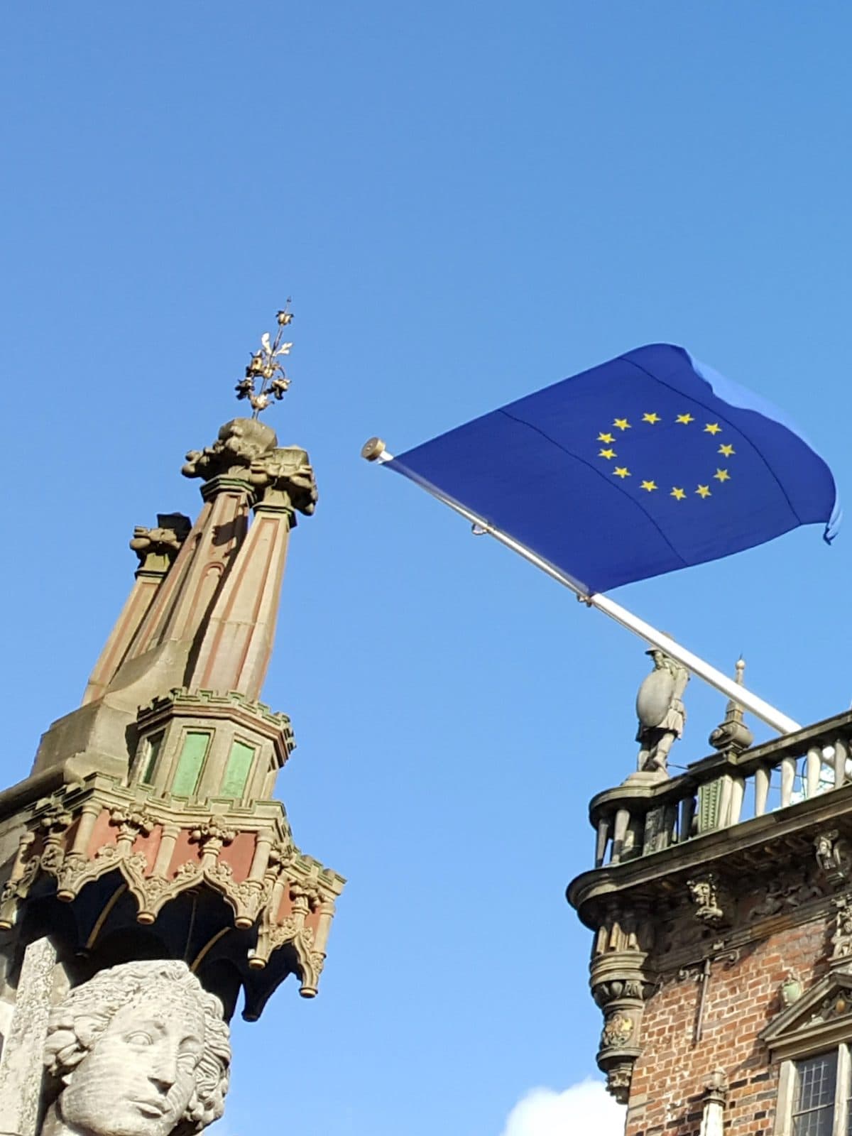 Der Kopf der Rolandstatue in Bremen neben der Europaflagge am Rathaus